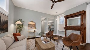 A living room with a sofa, chairs, a coffee table, a fireplace, and a ceiling fan. - Lux Historic 2BR near Stadiums, Downtown (Cincinnati)