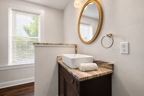 A bathroom with a white sink, marble countertop, and a gold-framed mirror. - Lux Historic 2BR near Stadiums, Downtown (Cincinnati)