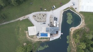 An aerial view of a lakeside property with a parking area, a swimming pool, and a boat dock.
