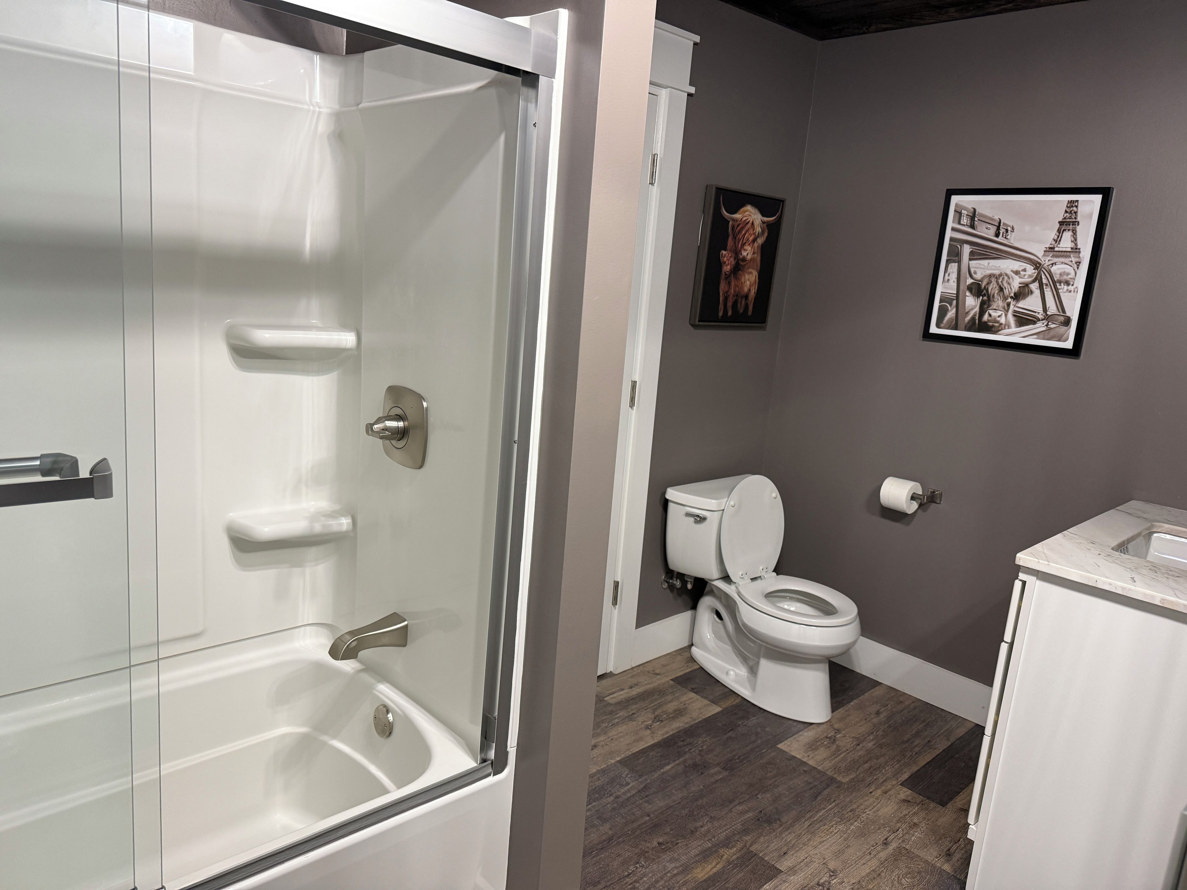 A bathroom with a glass-enclosed shower, a toilet, and a sink.