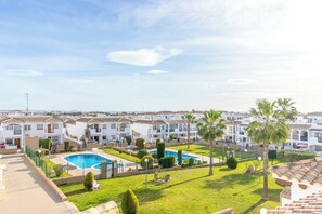 A residential area with multiple white buildings, a swimming pool, and well-maintained green lawns. - CB Living - Homely apartment Ciñuelica, Punta Prim (Alicante / Alacant)