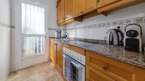 Een keuken met houten kastjes, een granieten aanrecht, een fornuis en een waterkoker.