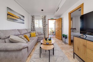 A modern living room with a sofa, coffee table, and a TV. - CB Living - Homely apartment Ciñuelica, Punta Prim (Alicante / Alacant)