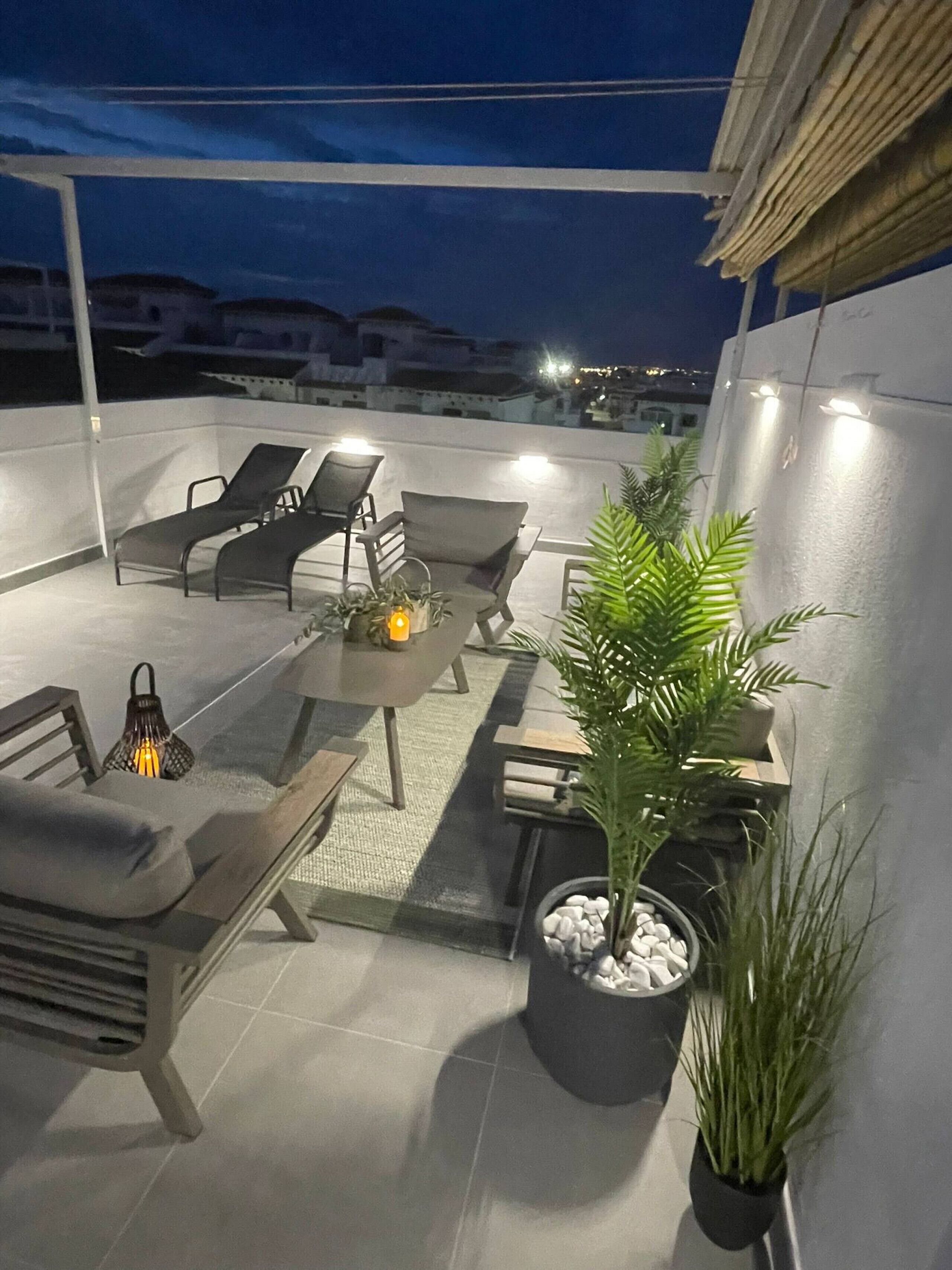 Un patio al aire libre con una mesa, sillas y plantas en macetas.