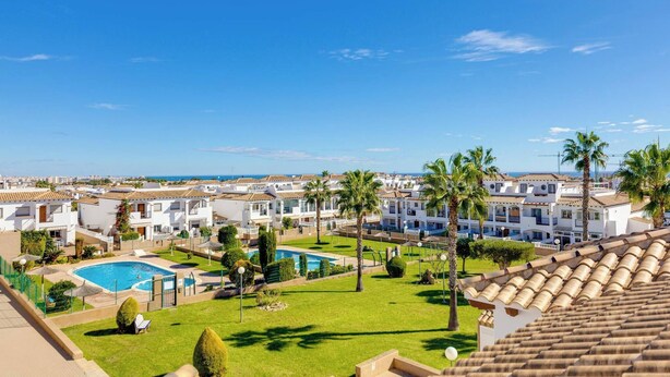 Een resort met meerdere gebouwen, een zwembad en palmbomen.