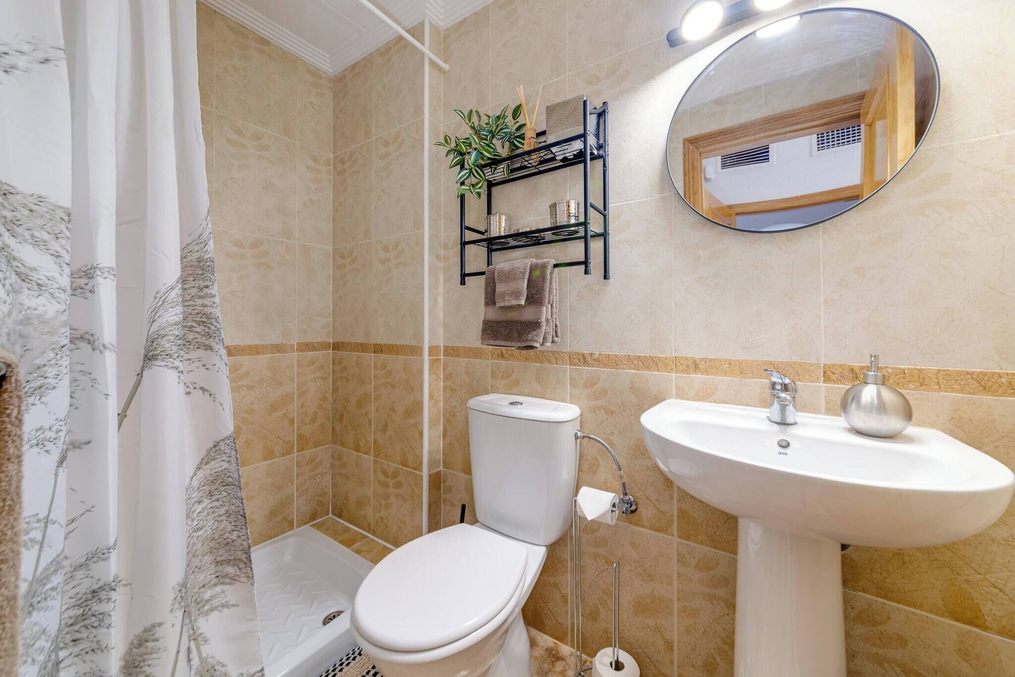 Een badkamer met toilet, wastafel, douche en spiegel.