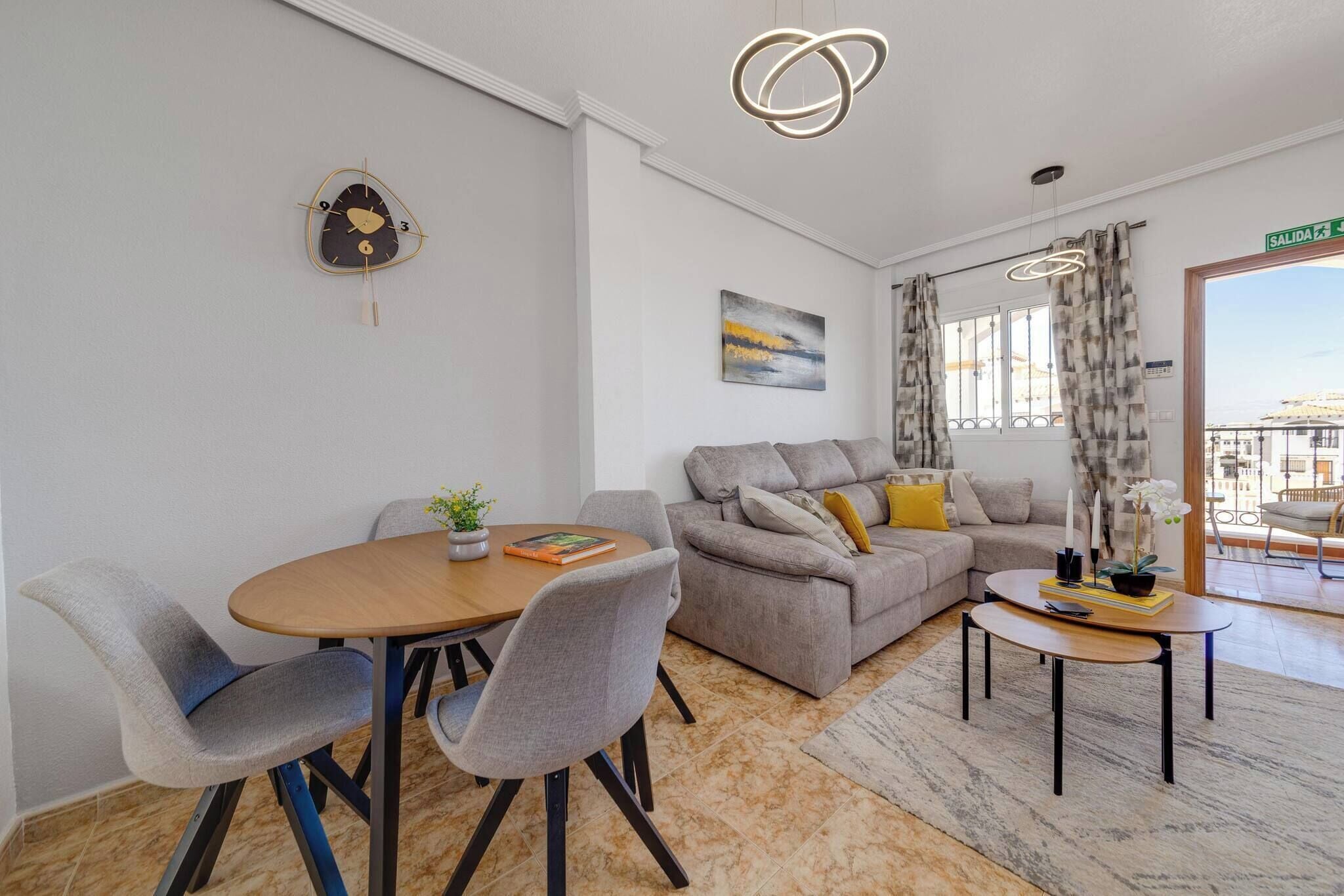 Ein modernes Wohnzimmer mit Essbereich, einer Couch, einem Couchtisch und einer außergewöhnlichen Wanduhr.
