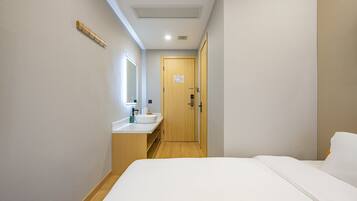 Una habitación de hotel con cama, baño con lavamanos y una puerta.