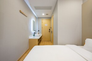 Quarto de hotel com uma cama, banheiro com pia e uma porta.