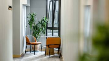 A hallway with two chairs, a table, and a large window.