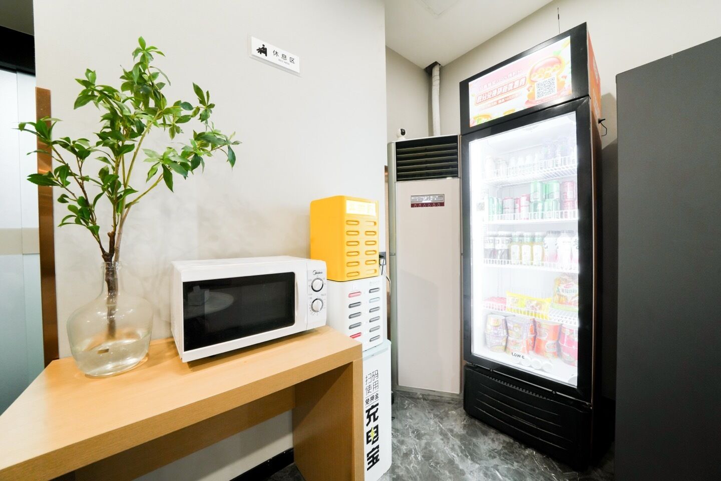 Una habitación con microondas, máquina expendedora y refrigerador.