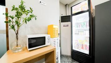 Una habitación con microondas, máquina expendedora y refrigerador.