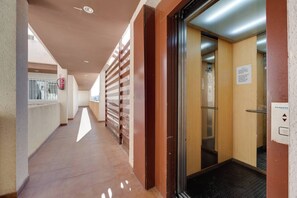 A corridor with a fire extinguisher, a wooden door, and an elevator. - CB Living - Apartment with roof terrace Aguamarina (Orihuela)