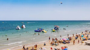 Una spiaggia con persone, strutture gonfiabili sull'acqua e imbarcazioni.