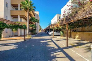 A street lined with buildings, parked cars, and palm trees. - CB Living - Apartment with roof terrace Aguamarina (Orihuela)