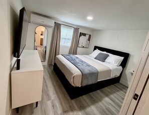 Een moderne hotelkamer met een bed, nachtkastje en televisie.
