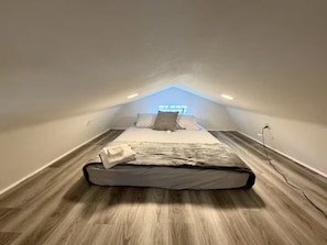 A small, sloped ceiling room with a bed, a window, and a power outlet. - Safari Tiny House Escape Nice, quiet, and private (Tampa)
