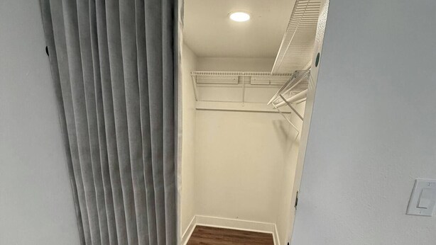 Um corredor estreito com piso de madeira que leva a uma escada com corrimão de metal.