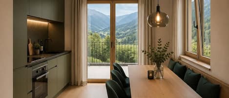 A modern kitchen with a dining area, large windows, and a view of the outdoors.