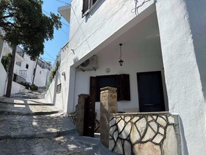 A narrow street with white buildings, stone steps, and a stone wall with a geometric pattern.