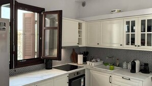A kitchen with white cabinets, a black oven, a sink, and a patterned tablecloth.