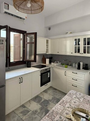 A kitchen with white cabinets, a black oven, a sink, and a patterned tablecloth. - SimpleGreece Skyros comfortable accommodation, traditional settlement, 56 sq.m. (Skyros)