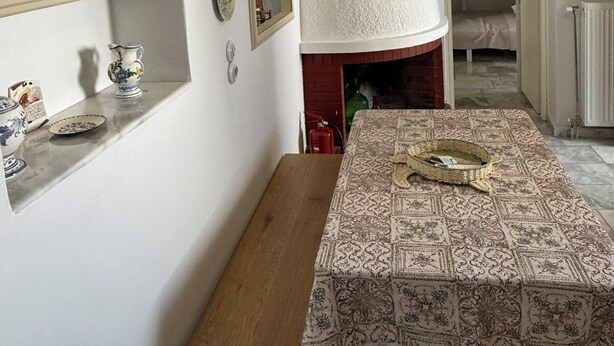 A dining area with a wooden table, a bench, and a patterned tablecloth.