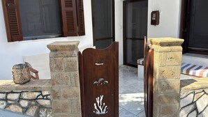 A stone entrance with a wooden door featuring a carved design, a wicker basket, and a stone bench.