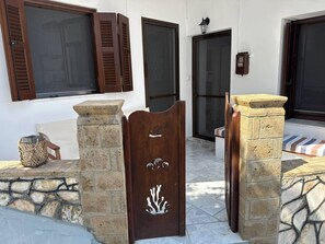 A stone entrance with a wooden door featuring a carved design, a wicker basket, and a stone bench. - SimpleGreece Skyros comfortable accommodation, traditional settlement, 56 sq.m. (Skyros)