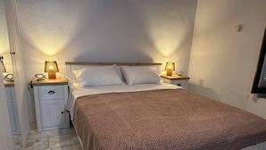 A bedroom with a bed, two bedside tables, and lamps.