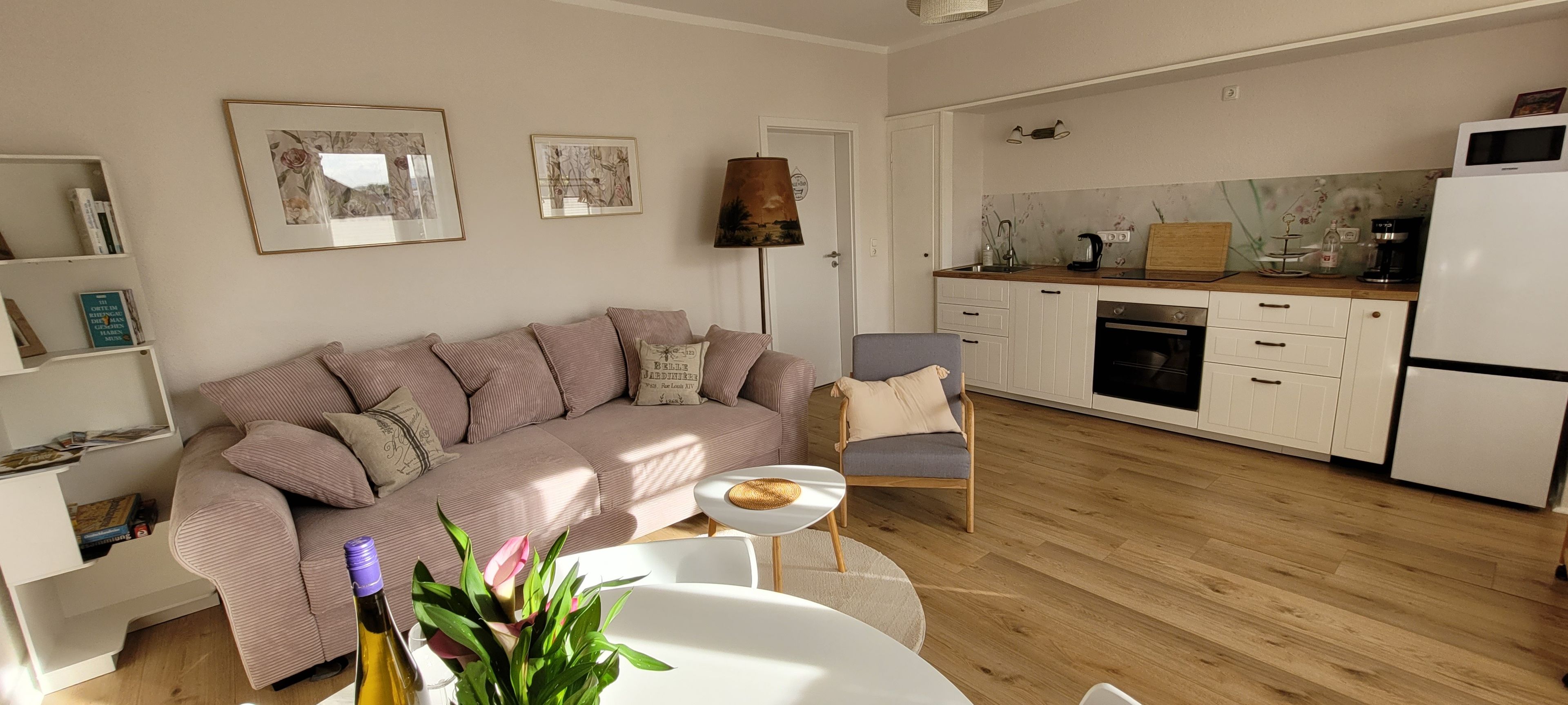 Una sala de estar moderna con un sofá, una mesa de comedor y una zona de cocina con armarios y electrodomésticos.