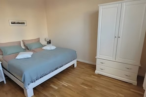 A bedroom with a bed, bedside table, lamp, and a wardrobe.