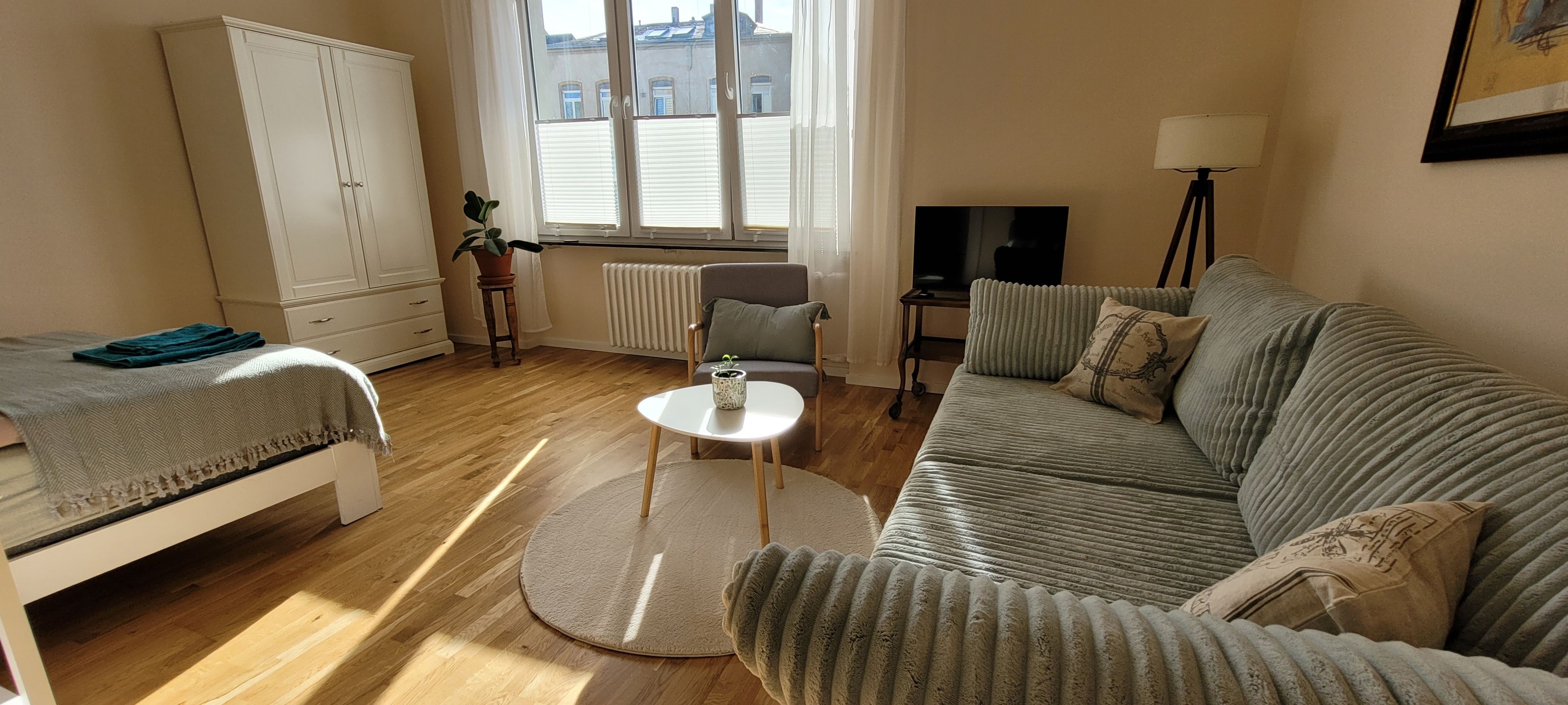 Ett möblerat vardagsrum med en soffa, ett litet runt bord, en tv och ett skåp.