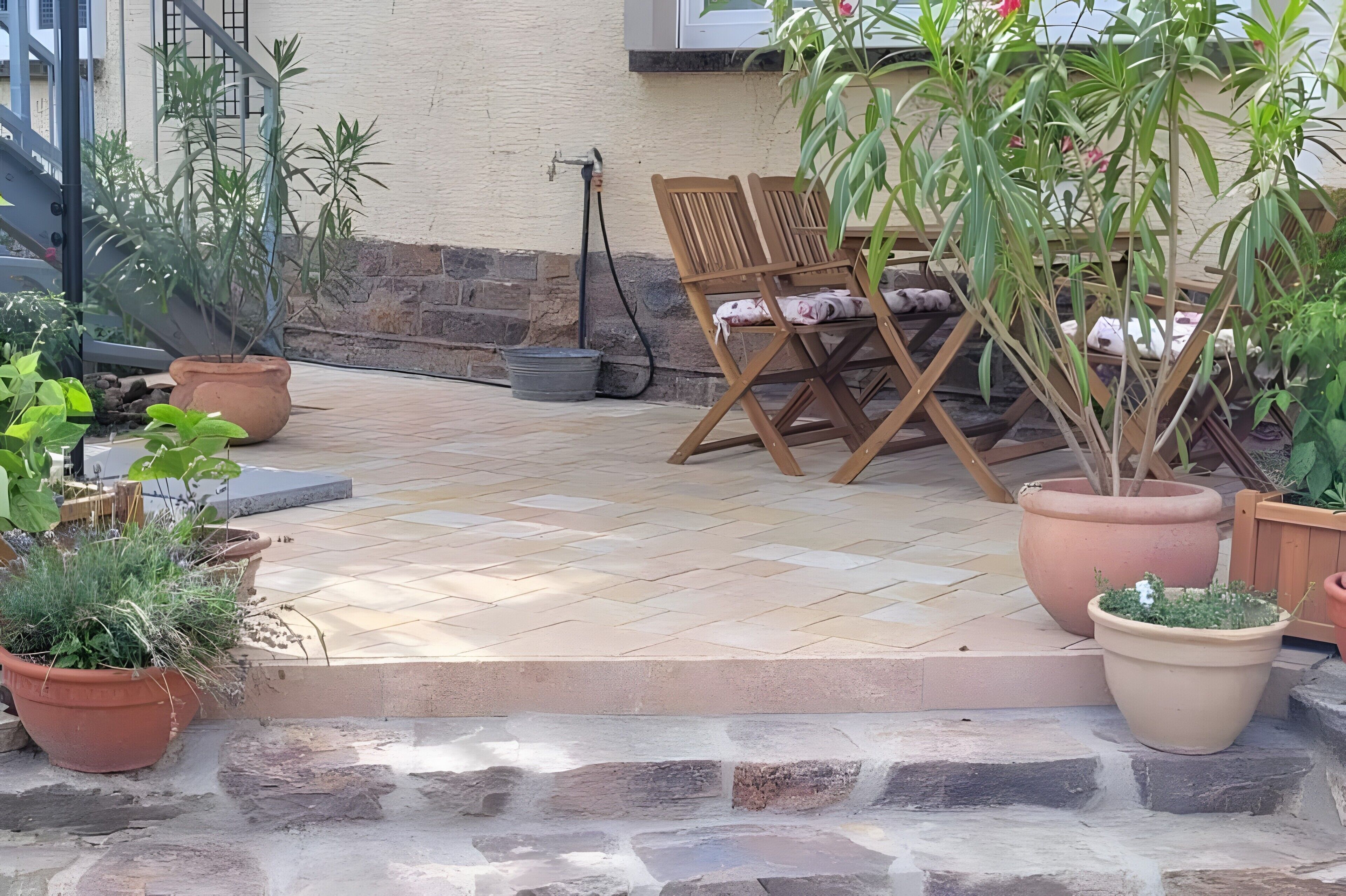 A patio with a seating area, potted plants, and a stone wall.
