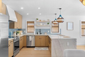Une cuisine moderne avec des meubles en bois, des appareils en acier inoxydable, un lave-vaisselle intégré et un grand îlot central.