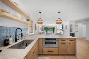 A modern kitchen with a central island, wooden cabinets, and pendant lighting. - Brand New - Gorgeous 3 Bedroom 3 Bathroom (Naples)