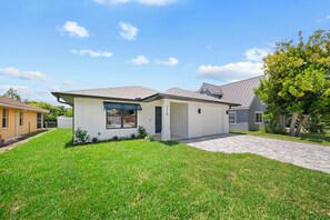 A single-story house with a garage, a well-maintained lawn, and a clear sky. - Brand New - Gorgeous 3 Bedroom 3 Bathroom (Naples)