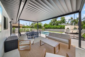 A covered outdoor patio with a pool, seating area, and barbecue grill. - Brand New - Gorgeous 3 Bedroom 3 Bathroom (Naples)