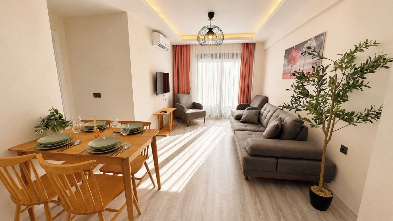 Ein modernes Wohnzimmer mit einer Couch, einem Esstisch und Stühlen. An der Wand befinden sich eine Pflanze und ein Gemälde.