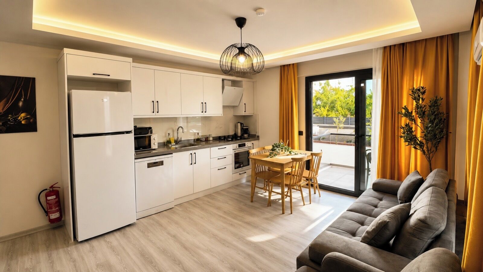 Une cuisine moderne avec des meubles blancs, une table à manger avec des chaises et un canapé dans un salon donnant sur l’extérieur.