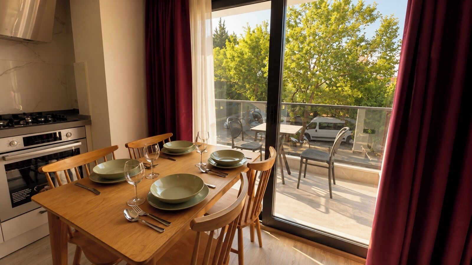 A dining area with a table set for four, a kitchen with modern appliances, and a view of the outdoors through large windows.