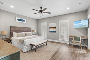 Ein Schlafzimmer mit Bett, Nachttischen, einem Schreibtisch, einem Sessel sowie Kunstwerken an den Wänden.
