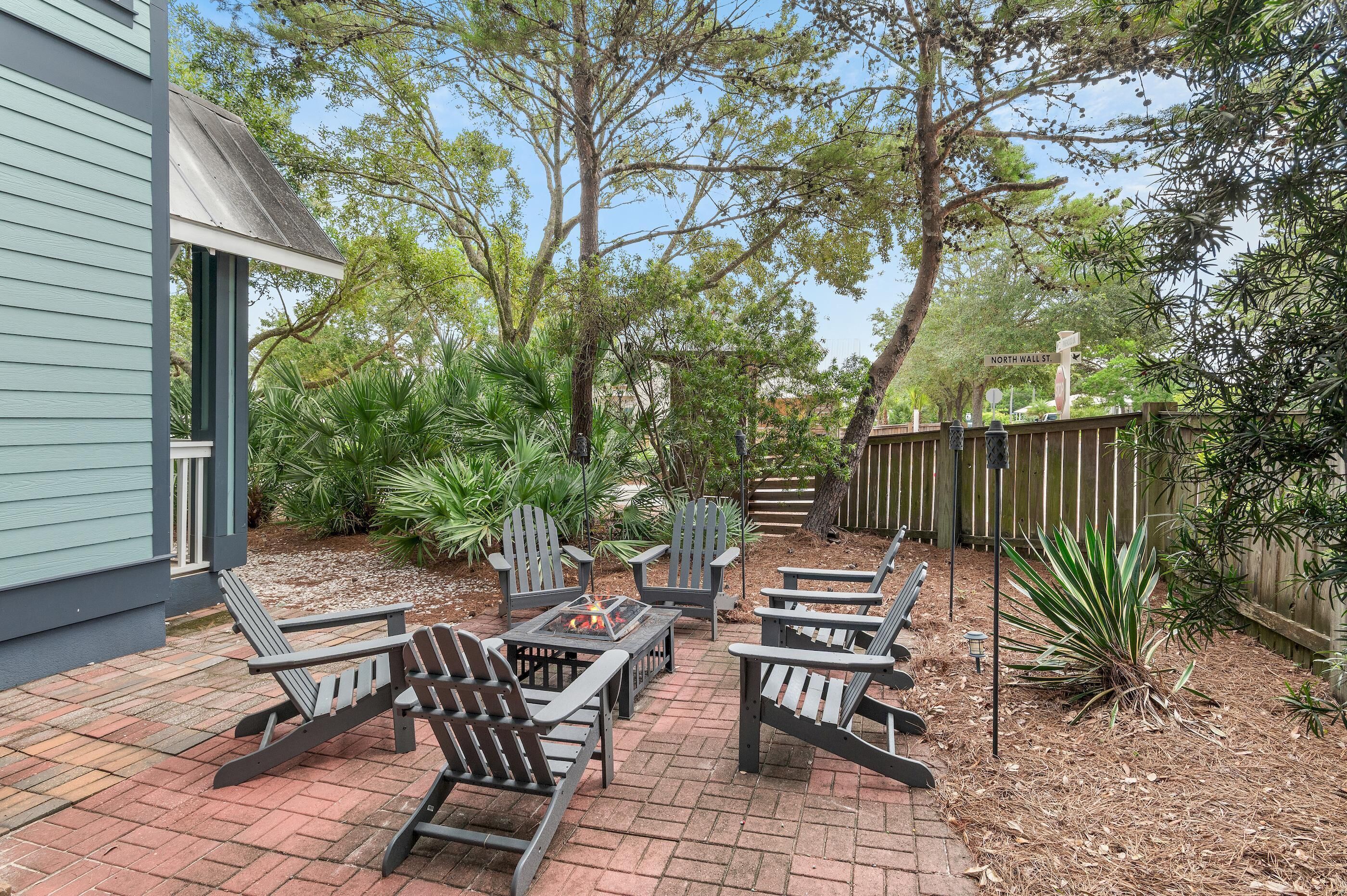 Une terrasse extérieure avec des fauteuils Adirondack et un foyer.