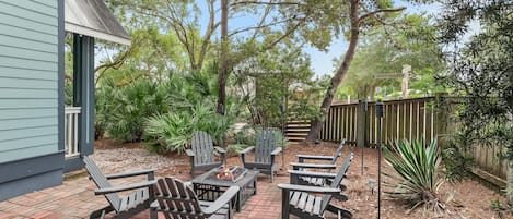 Un patio al aire libre con sillas Adirondack y una chimenea.