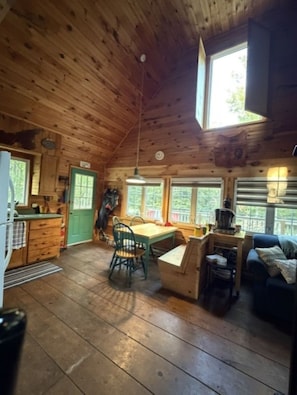Interior d'una cabana de fusta amb zona de menjador, cuina i espai d'estar acollidor.