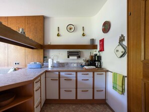 A kitchen with wooden cabinets, a countertop, and various appliances including a coffee maker and a kettle. - Villa zur Gondel, Garden & Mountain Views (Waidring)