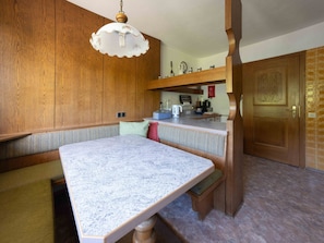 Una cocina con armarios de madera, encimera de mármol y una lámpara colgante.