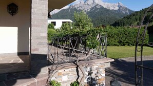 Una scala in pietra conduce a un balcone con ringhiera in metallo che si affaccia su un paesaggio montuoso.