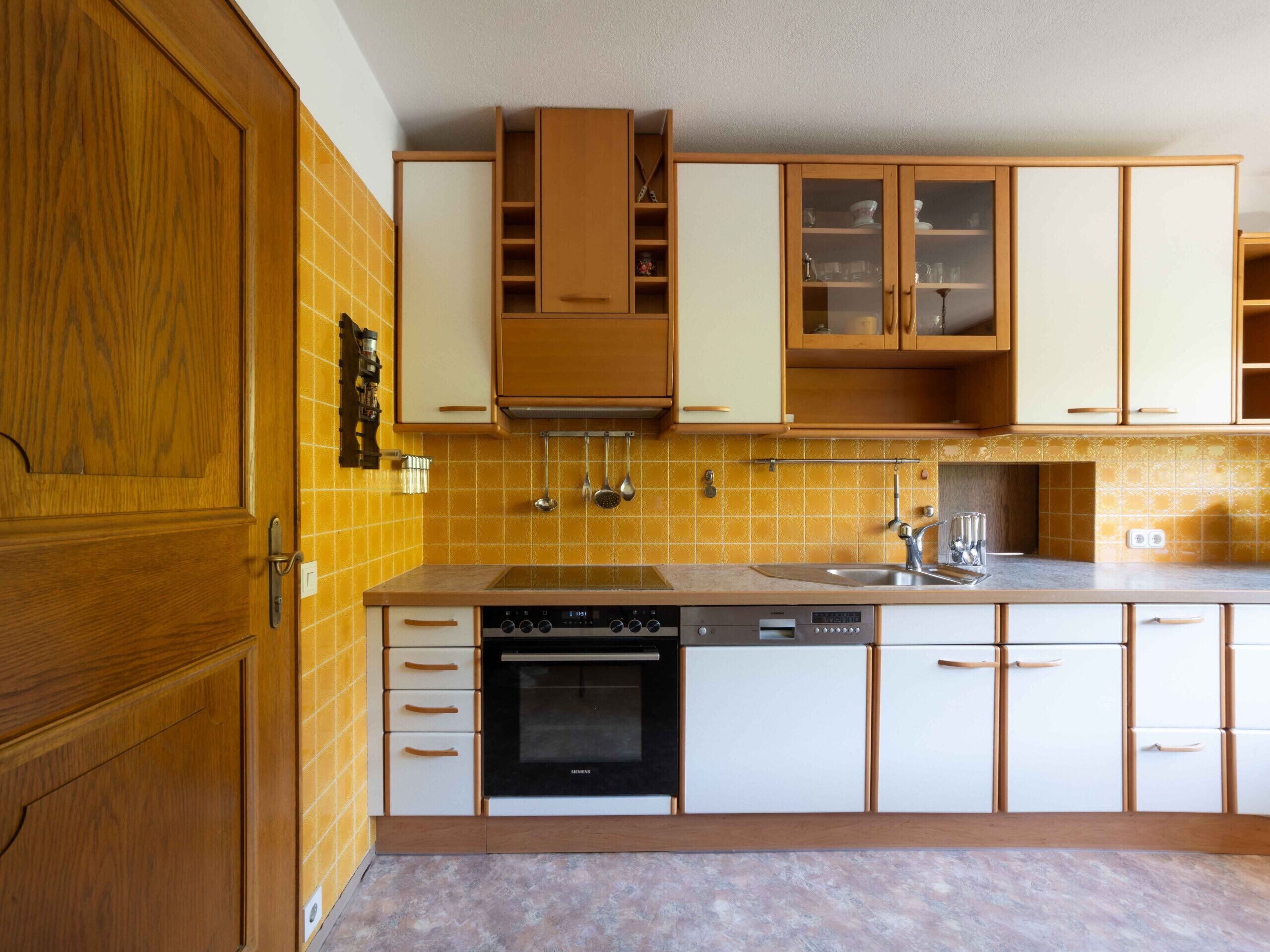 Une cuisine avec des meubles en bois, un four encastré et un évier.