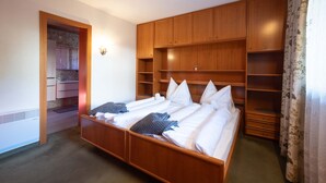 Una camera d'albergo con un letto grande, un armadio in legno e un bagno visibile attraverso una porta aperta.